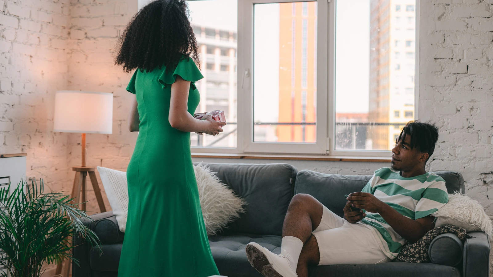 Una coppia si gode un momento di relax in un luminoso e moderno soggiorno con regali e posti a sedere confortevoli. — SHVETS production – Pexels
