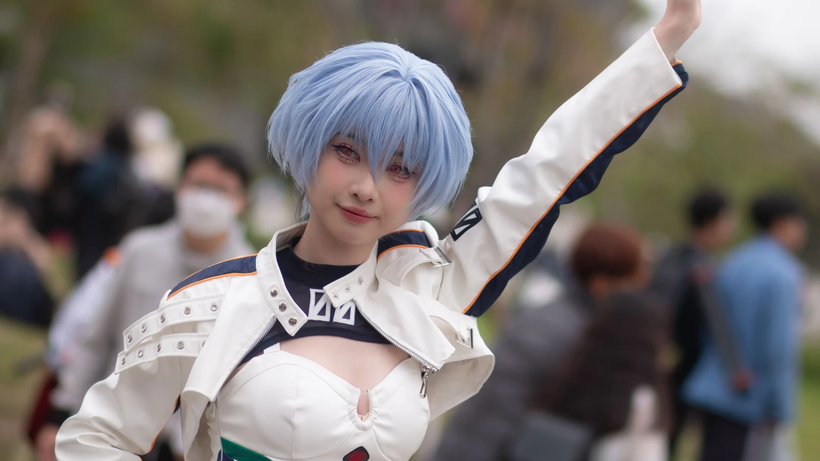 Una cosplayer con un costume appariscente e i capelli blu posa con sicurezza a un raduno all'aperto.