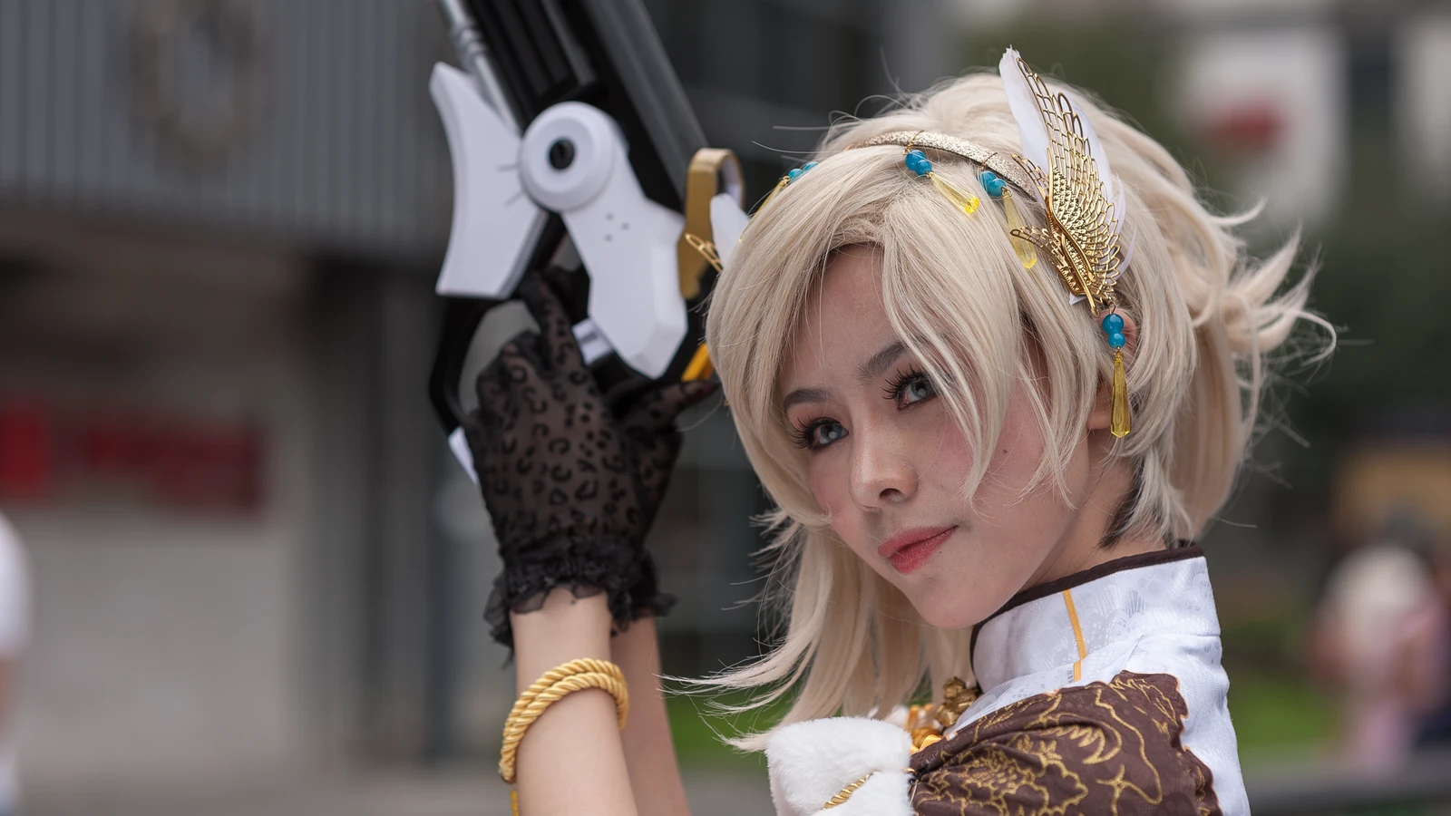 Cosplayer con costume intricato e pistola di scena, in posa all'aperto durante il giorno.
