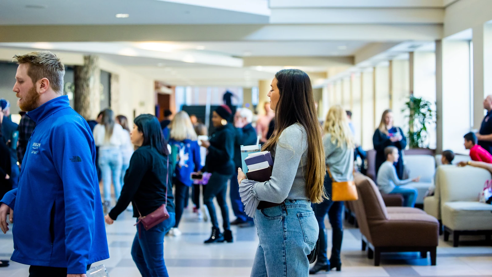 Un vivace corridoio universitario con studenti di diverse etnie che interagiscono e si muovono.
