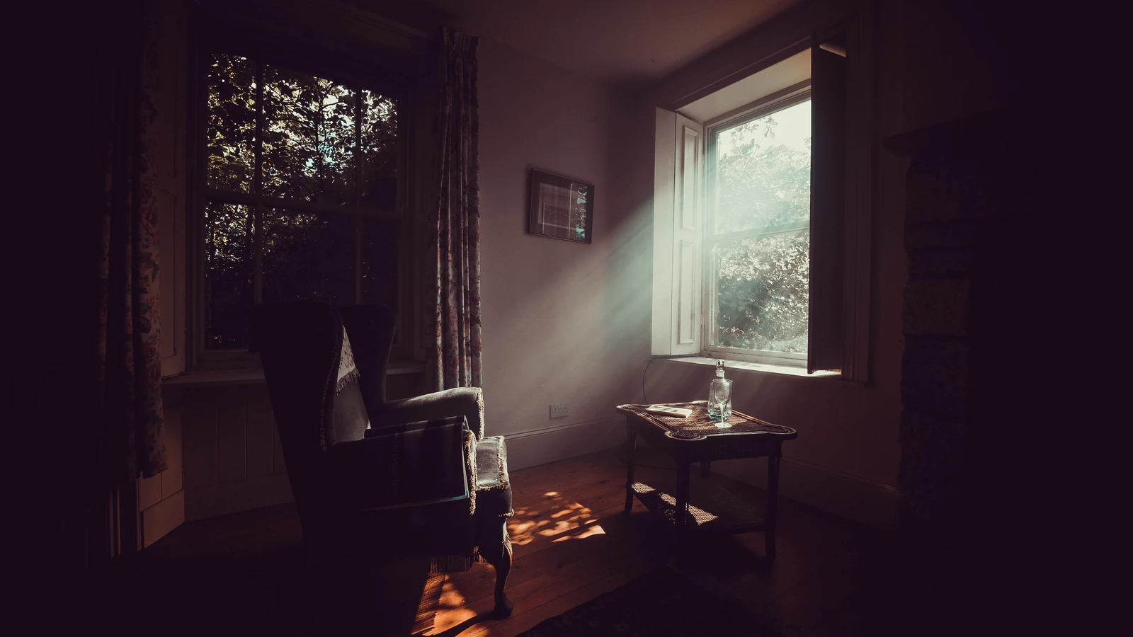 Una serena stanza vintage con la luce del sole che filtra dalla finestra, evidenziando una poltrona accogliente e mobili in legno.