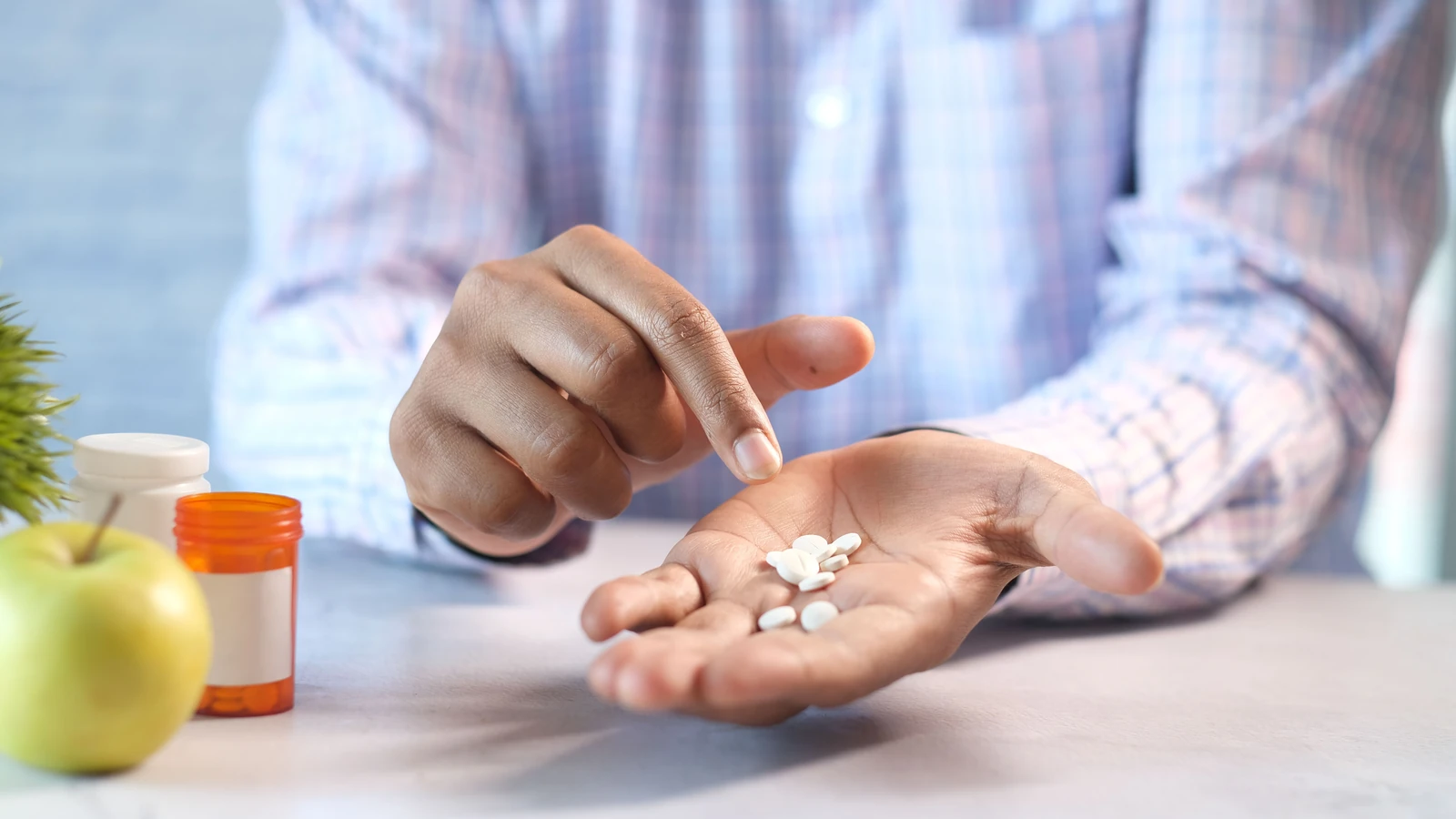 Primo piano delle mani di un uomo che tiene e punta a pillole bianche accanto a una bottiglia di prescrizione. — Towfiqu barbhuiya – Pexels