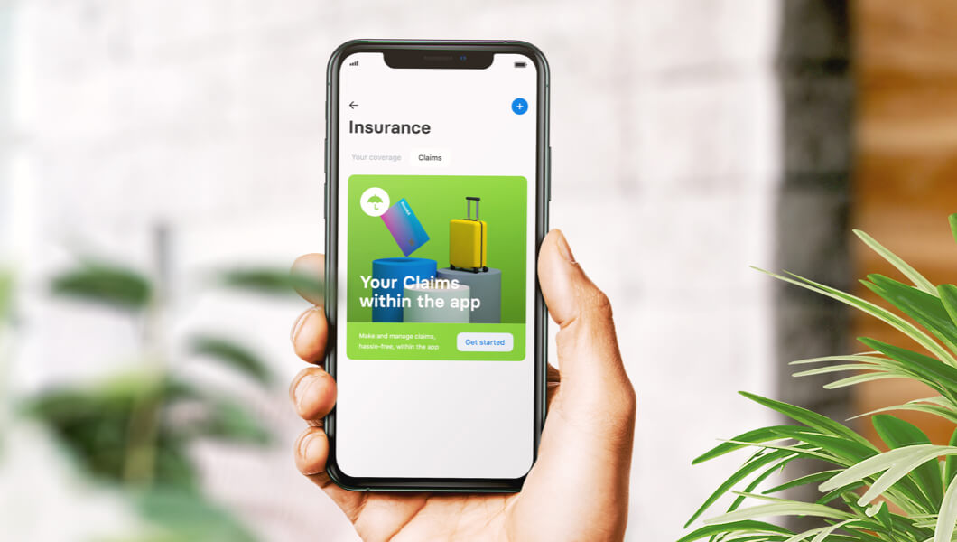 Hand holding mobile phone showing Revolut insurance with Qover