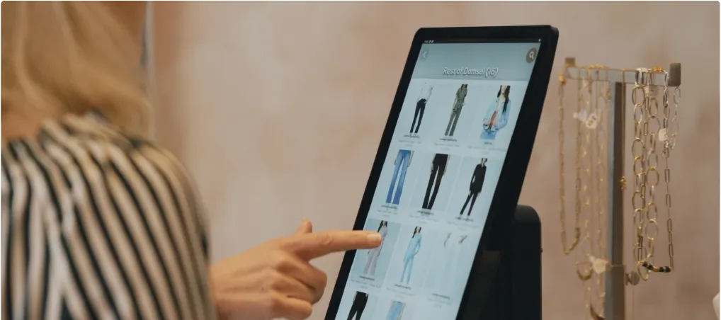 Deux acheteurs utilisent le site Cloudshelf pour choisir une paire de pantalons en denim.