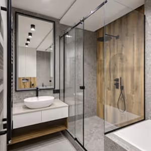 Modern bathroom with glass shower, wooden accent wall, white sink, and mirror reflecting ceiling lights.
