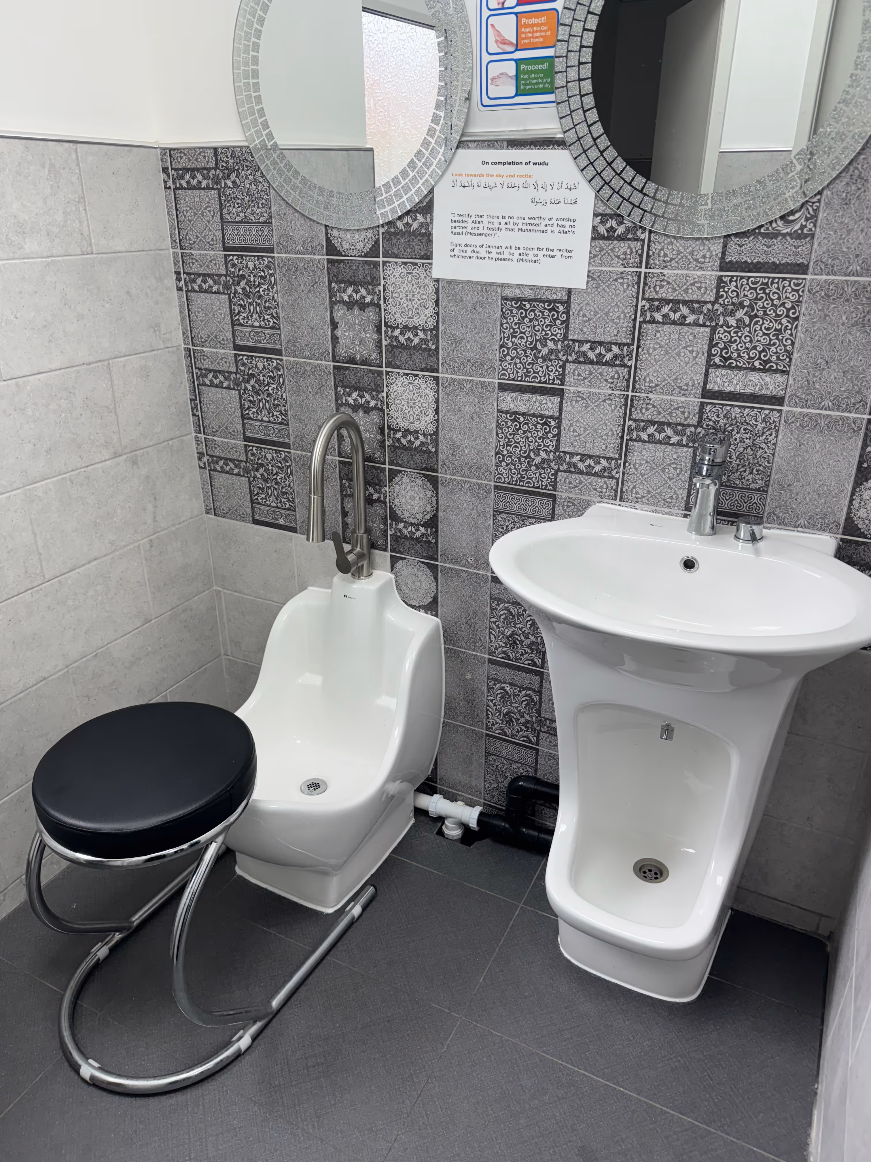 Bathroom corner with a white water basin with a faucet, a matching wash basin, stool, and decorative tile wall.