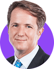 A headshot of a smiling man with short brown hair wearing a suit and tie edited within a simple circle graphic in a bright purple background.