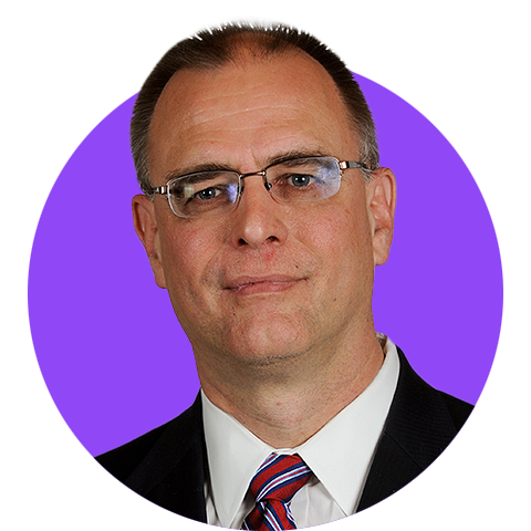 A headshot of a dark haired man wearing glasses in a suit edited within a simple circle graphic with a bright purple background.