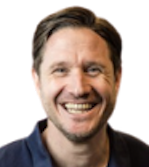 A headshot of a smiling man with short dark brown hair and a dark blue shirt edited within a simple circle graphic that has a bright purple background.