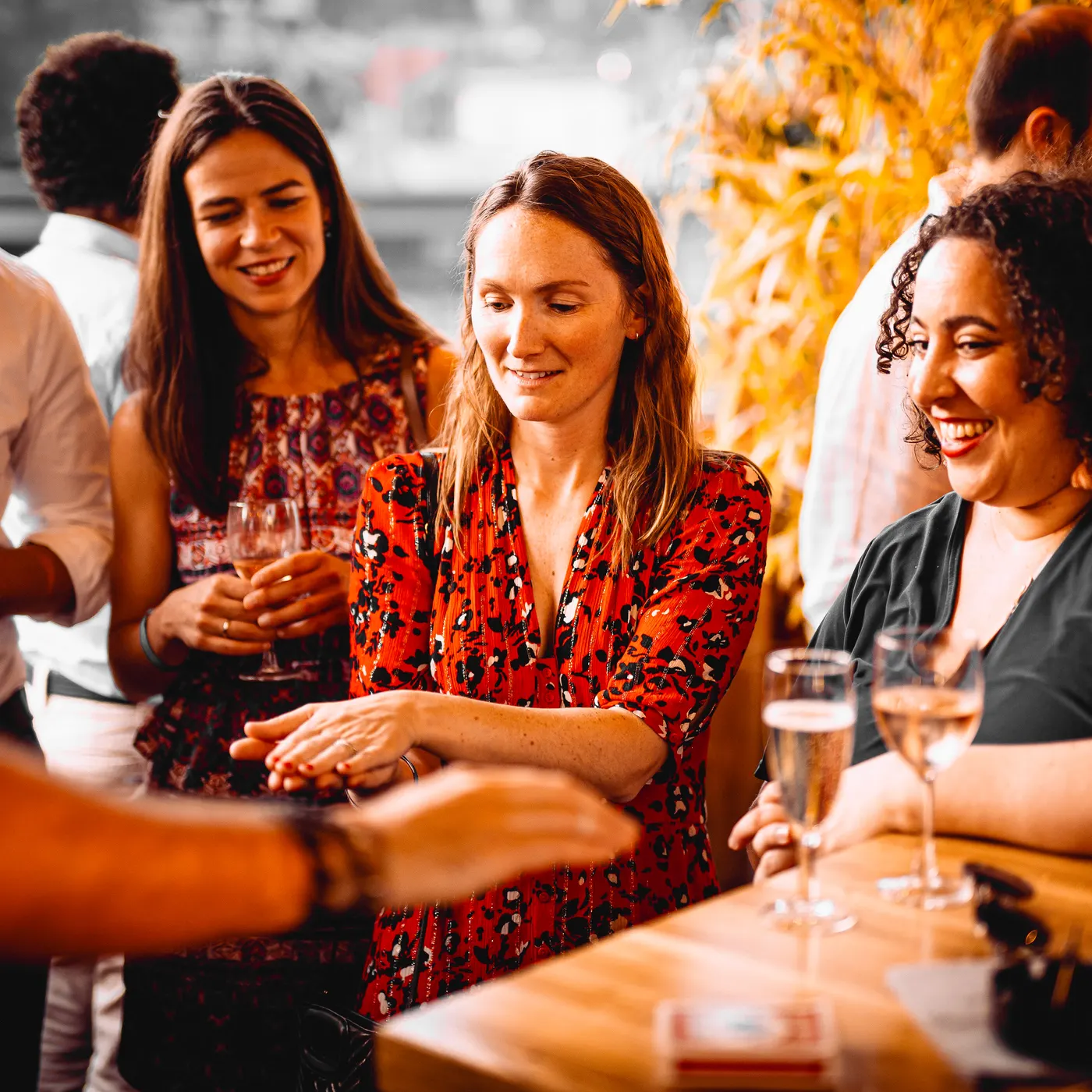 Des invitées attablées réagissent, émerveillées, à un tour de magie