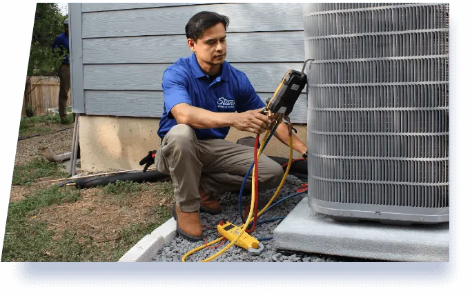 Technician from Stan's Heating, Plumbing, and Electrical performing maintenance on an outdoor air conditioning unit, using diagnostic tools.