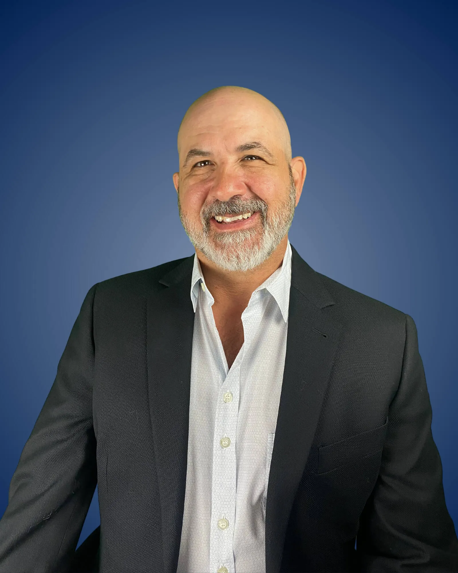 Mark Guarino in suit smiling in front of blue background.