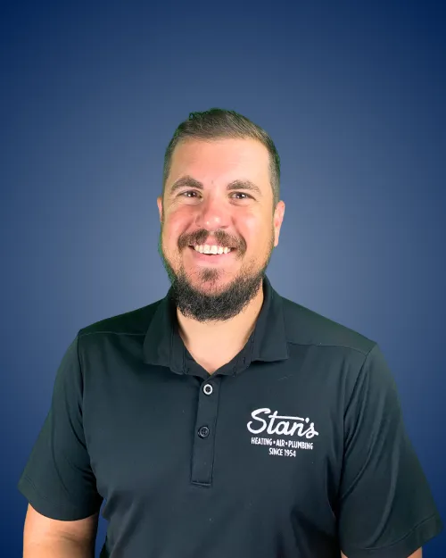 Kevin Borseth in Stan's Heating black shirt, smiling, blue background.