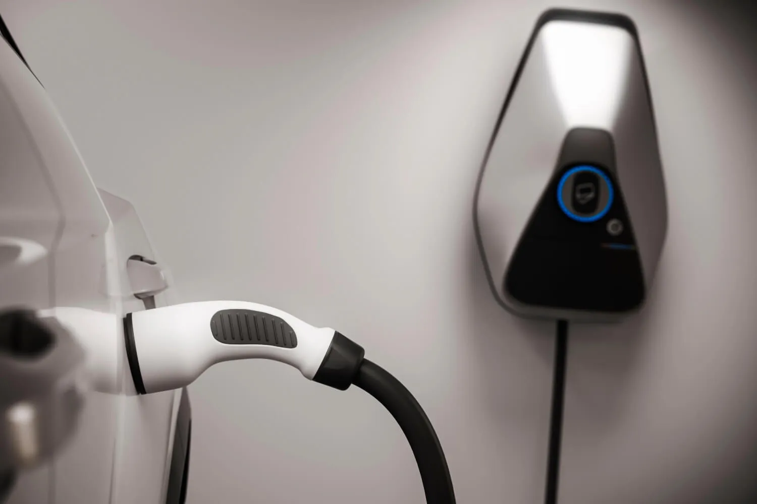 Electric vehicle charging station with a plugged-in charging cable.