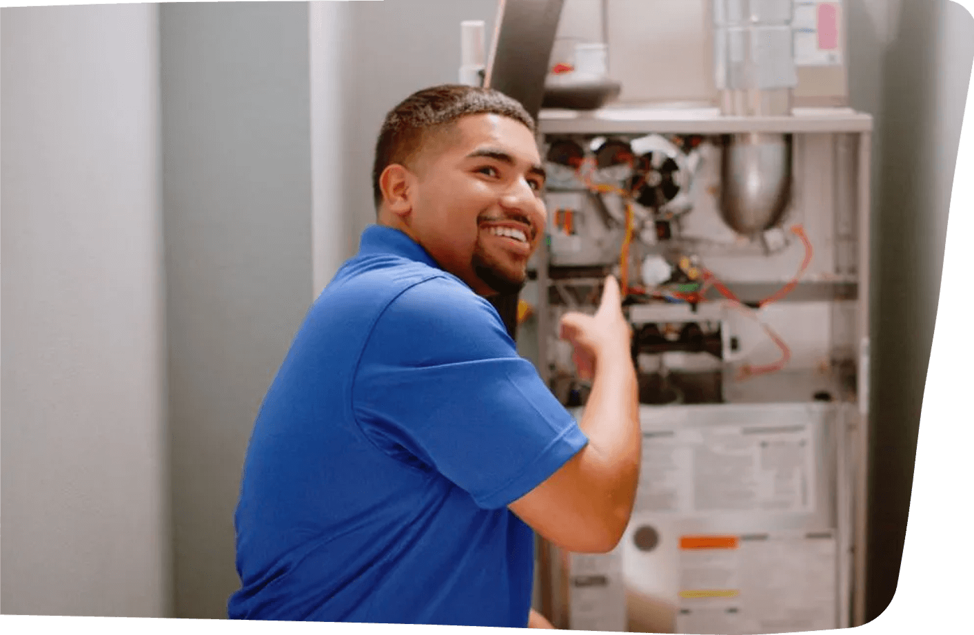 A technician wearing a blue shirt and holding a flashlight while inspecting an HVAC system in an attic, showcasing a detailed inspection process.
