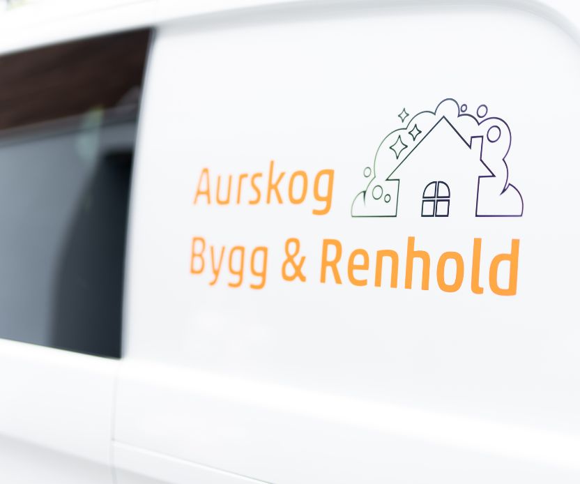 Skilt på hvit varebil med teksten Aurskog Bygg & Renhold og en stilisert huslogo.