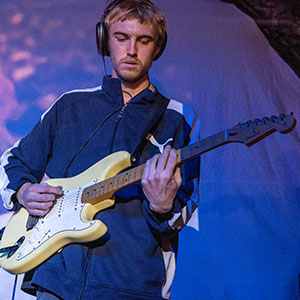 A dBs student playing electric guitar on a stage