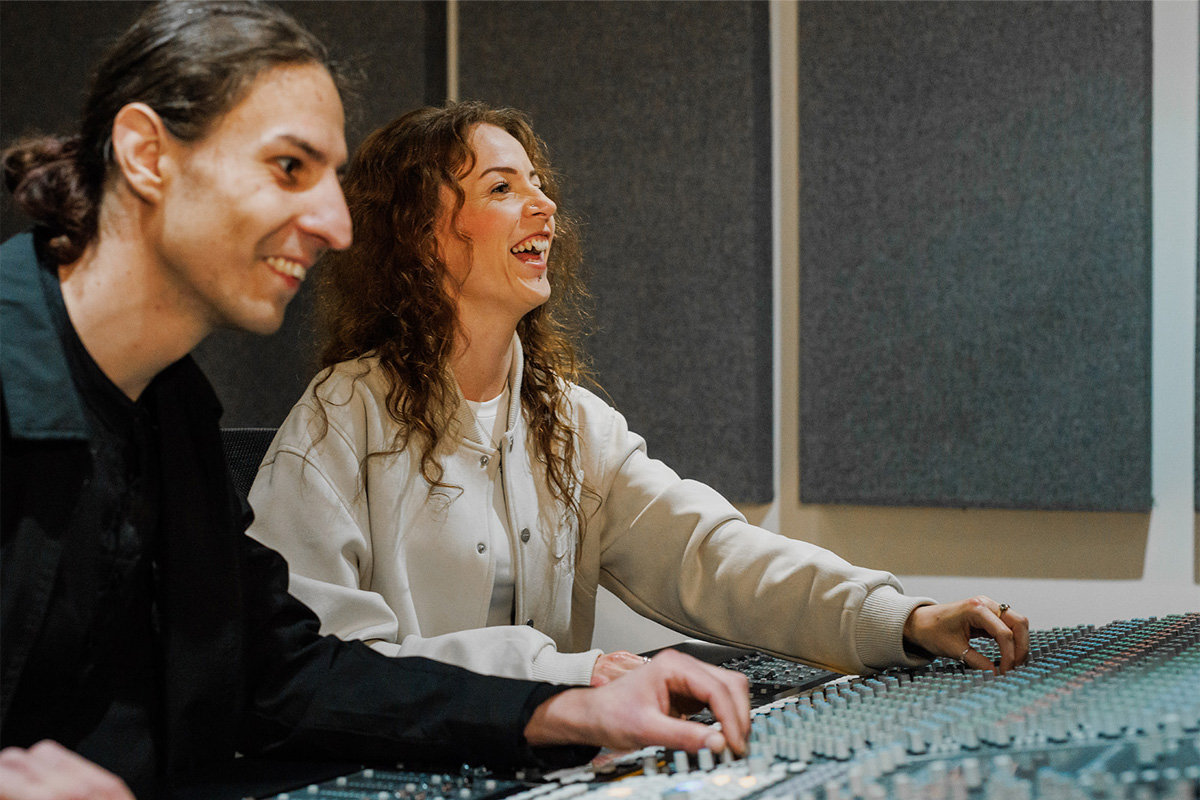 Two students smiling while using a mixing desk