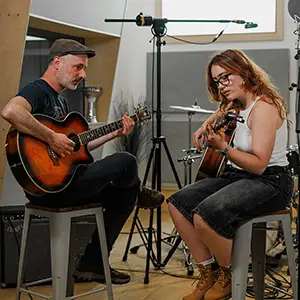 Student and Teacher play guitar in a studio setting