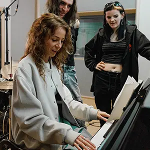 student standing around a piano composing music 