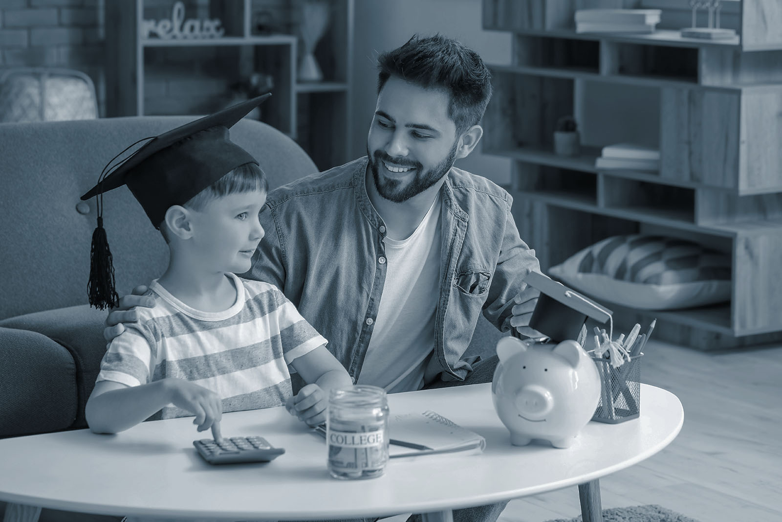 Father and young son in a graduation cap saving money in a college jar, blue duotone