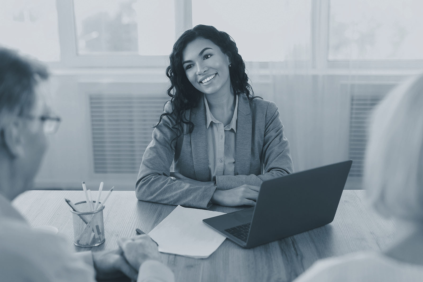A fee-only financial advisor meeting with a mature couple at a desk, blue duotone