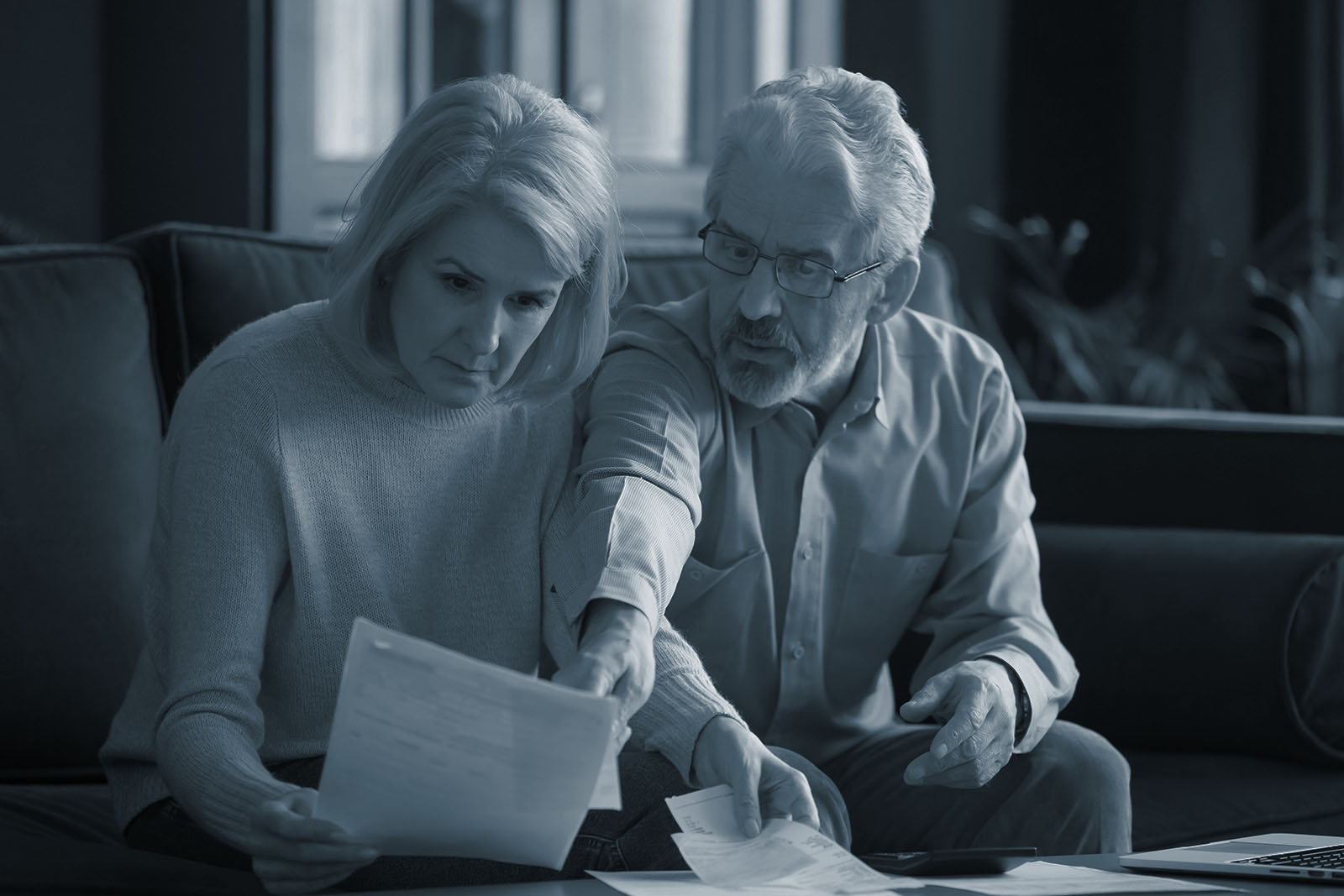 Mature couple reviewing retirement paperwork together at home, shown in Ignite's blue duotone style