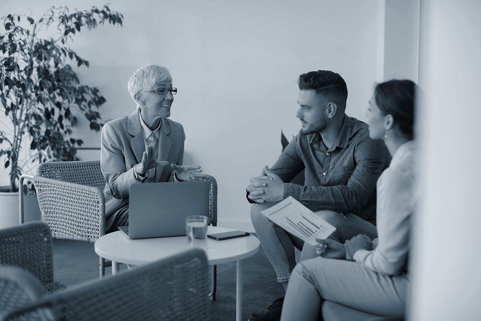 A financial adviser talking with a couple in an office, in Ignite Financial's blue duotone treatment