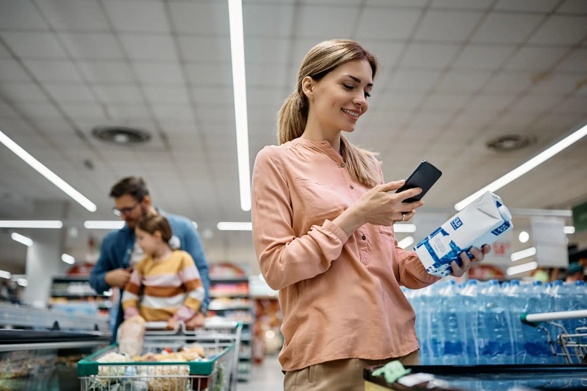 Woman authenticating product with a smartphone at a supermarket
