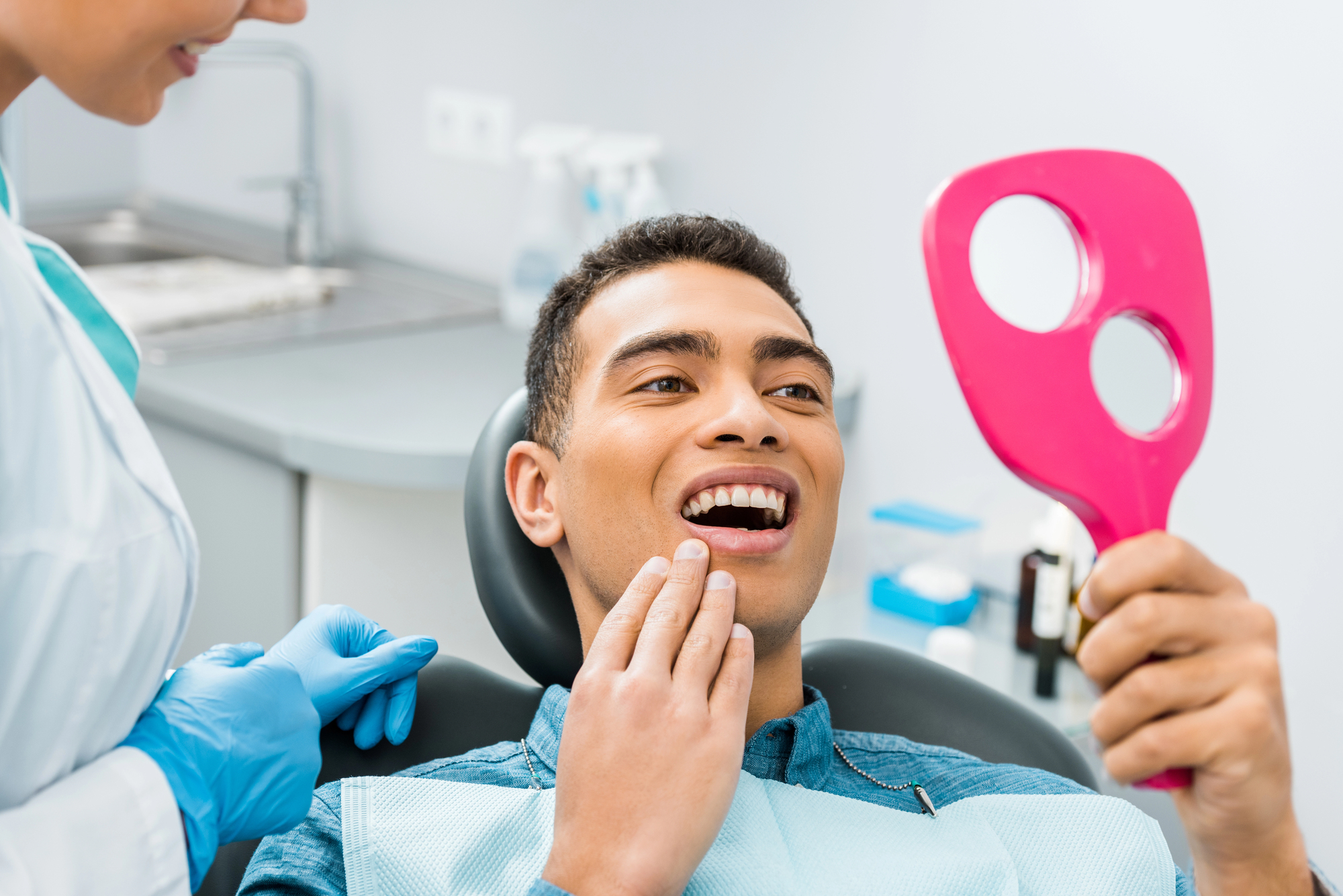 man smiling and looking in the mirror at the Dentist Miramar FL