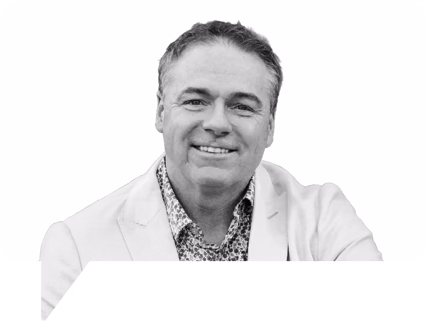 Smiling middle-aged man with short hair wearing a light-colored blazer and patterned shirt.