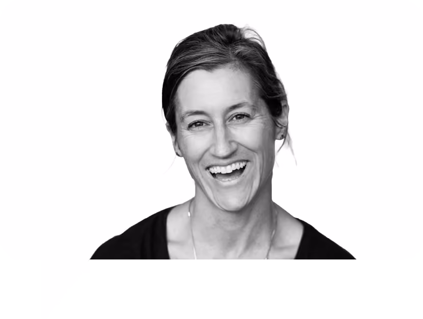 Black and white portrait of a woman smiling with hair pulled back and wearing a dark top.