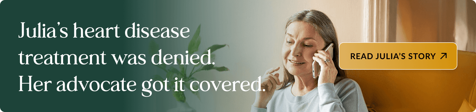 Middle-aged woman with blonde hair wearing a light blue sweater, smiling while talking on a phone, seated on a yellow chair with a plant visible in the background and natural lighting from a window. Banner text: Julia's heart disease treatment was denied. Her advocate got it covered. Includes a button: READ JULIA'S STORY.