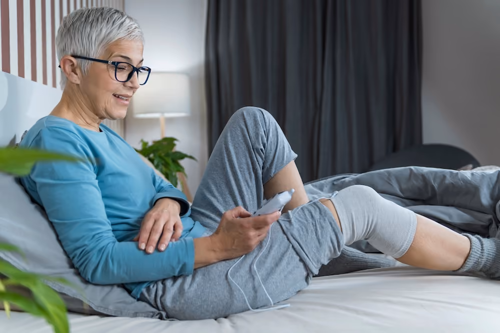 A senior woman using a TENS device
