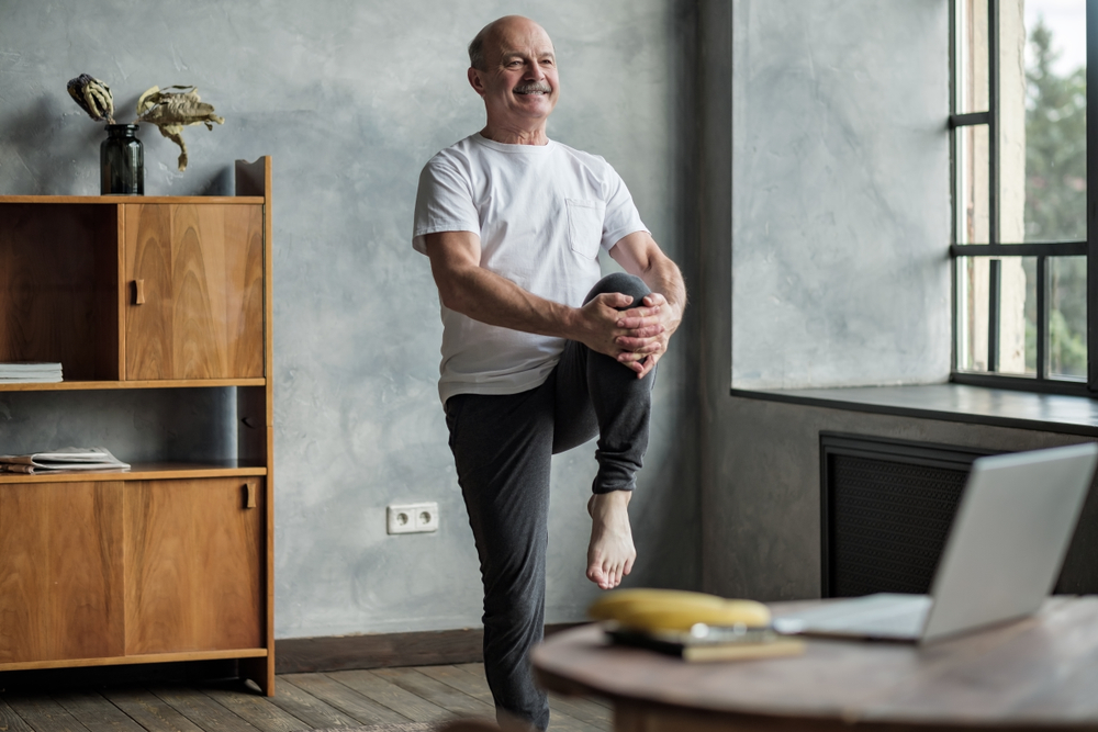 A senior man performing a standing leg raise