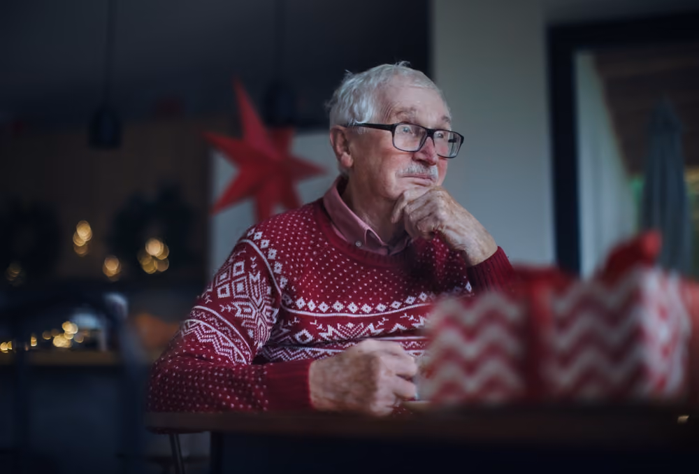 An older man, sad despite being surrounded by holiday decoration.