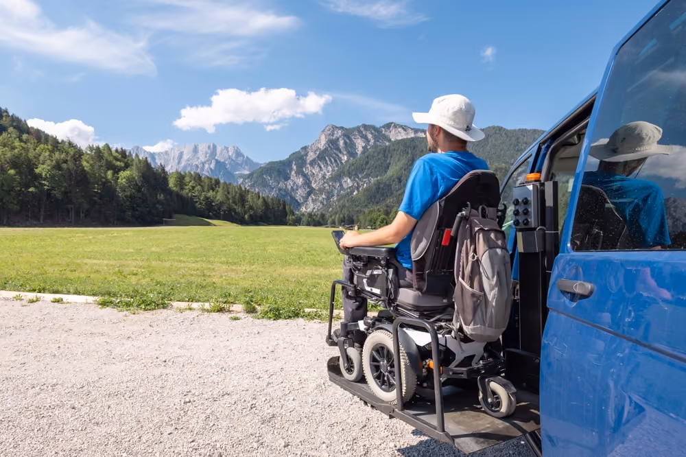A man being lifted out of his vehicle by a wheelchair transfer device.