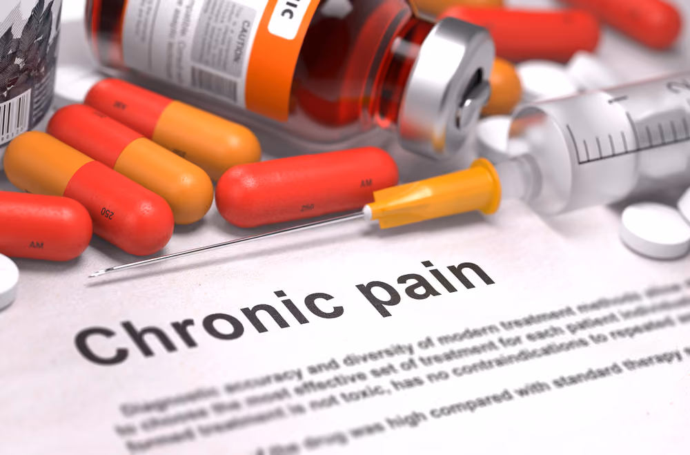A piece of paper that reads "Chronic Pain" amongst a sea of pills.