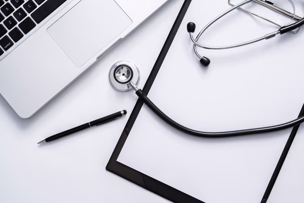 A doctor's desk, with laptop, stethoscope, etc.