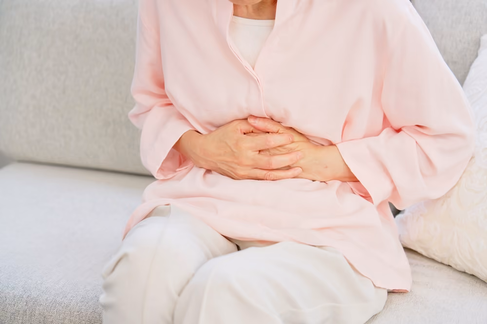 A senior woman clutching her stomach.
