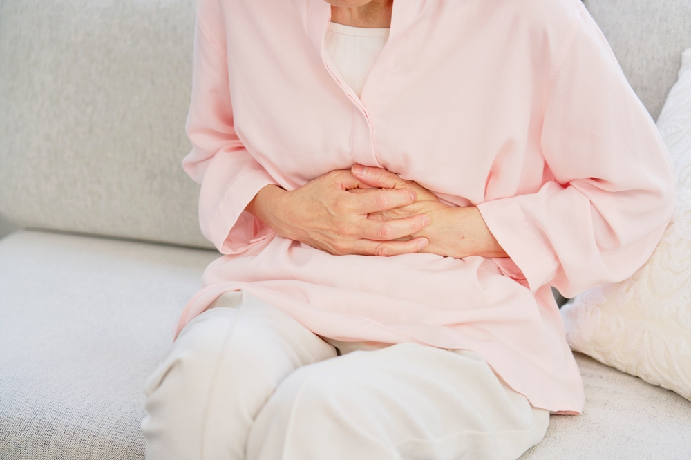 A senior woman clutching her stomach.
