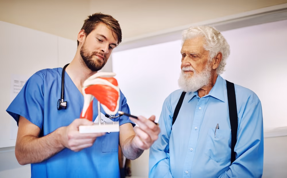 A man showing a doctor how his upcoming hip replacement surgery works.