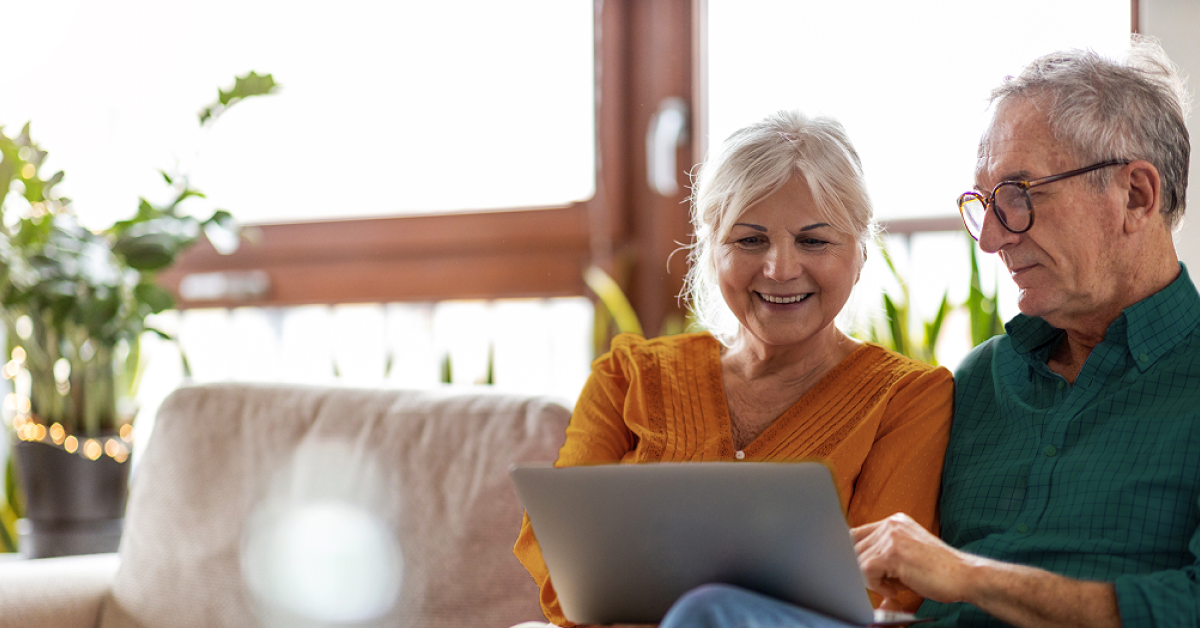 senior couple deciding medicare open enrollment on a laptop on a couch