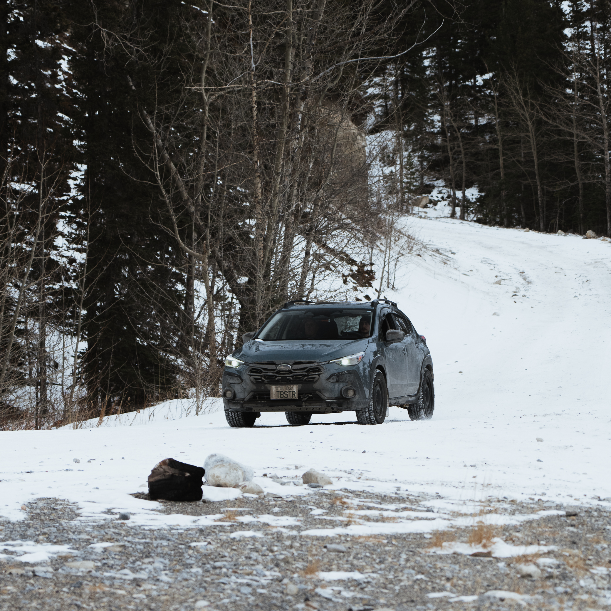 Subaru Crosstrek navigating a rocky snow-covered trail in the Canadian Rockies with skid plate protection