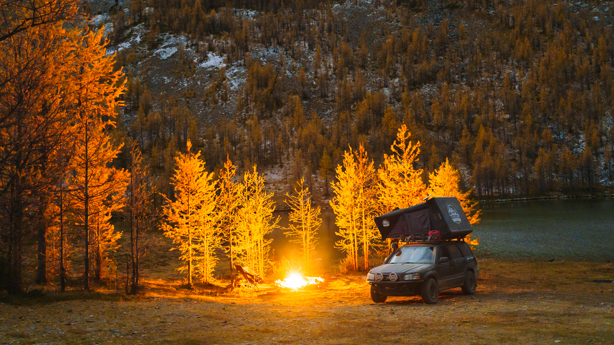Lifted Subaru Forester Offroad camping with a hybrid style roof top tent by a campfire