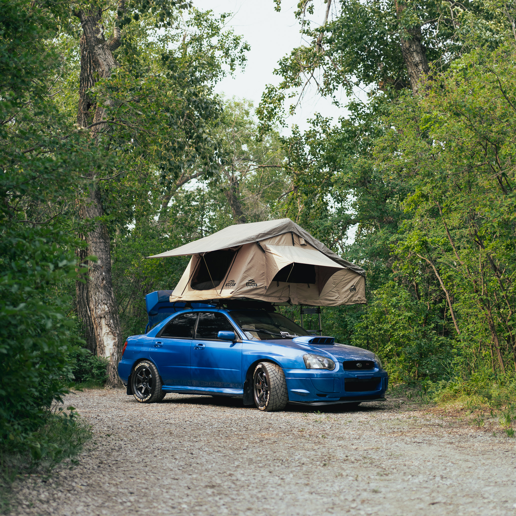 2004 Subaru STI with custom roof rack in a campsite with a roof top tent