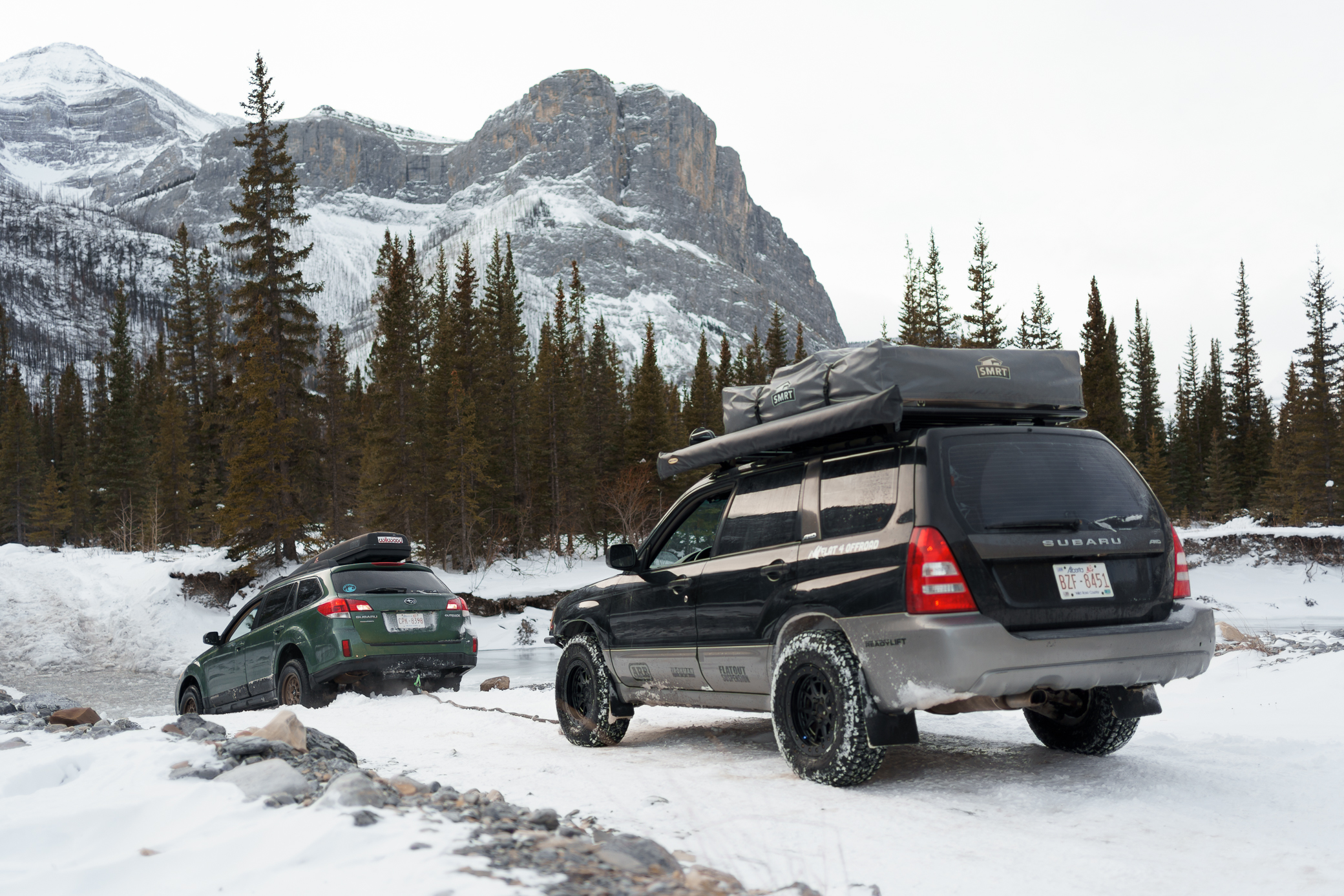 Lifted Subaru Forester pulling an Subaru Outback out of a icy river with a kinetic strap