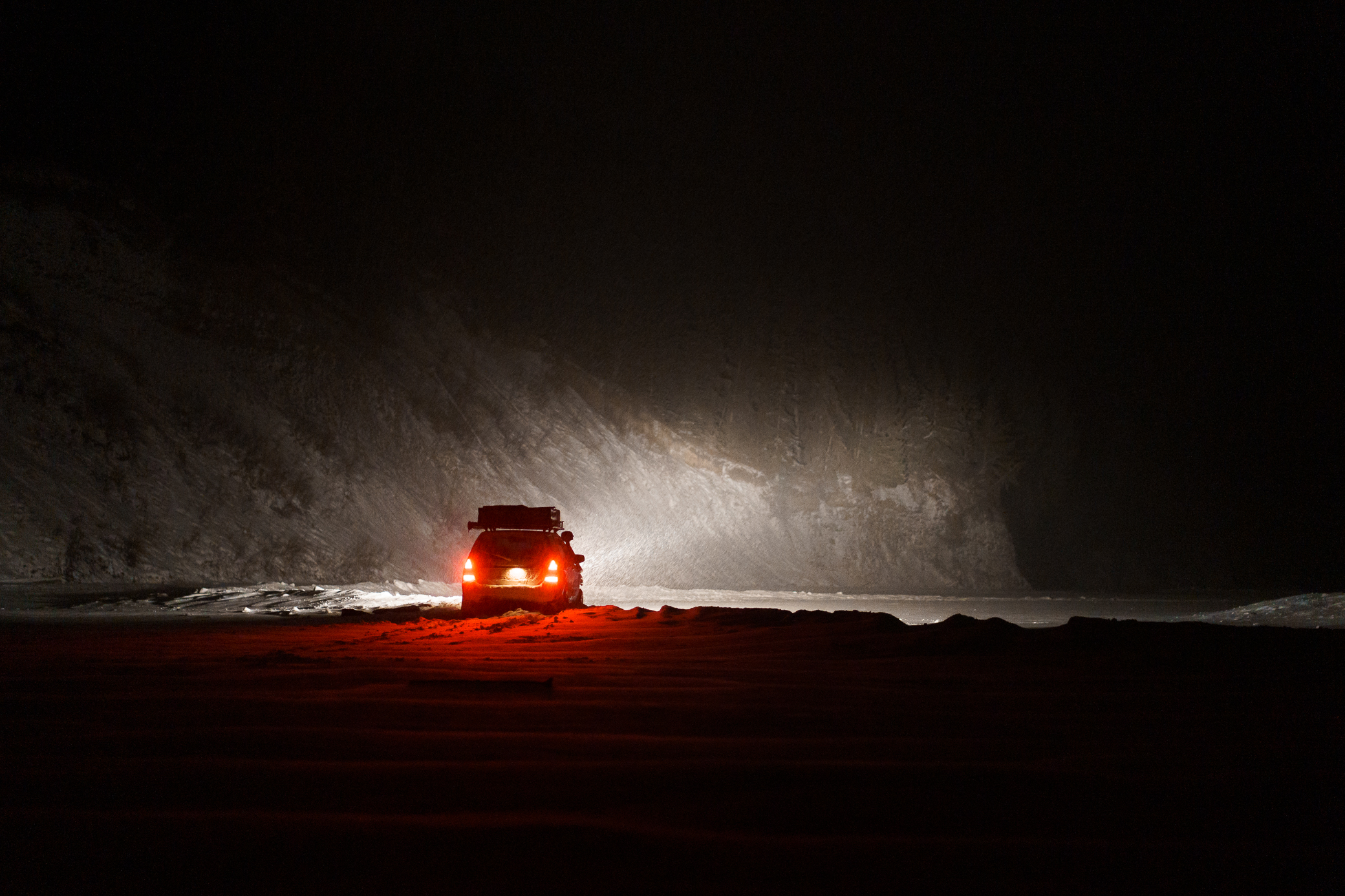 Subaru Forester with aftermarket lights on a frozen lake at night.