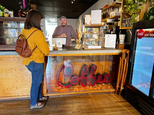 Customer smiles and laughs at coffee counter with barista