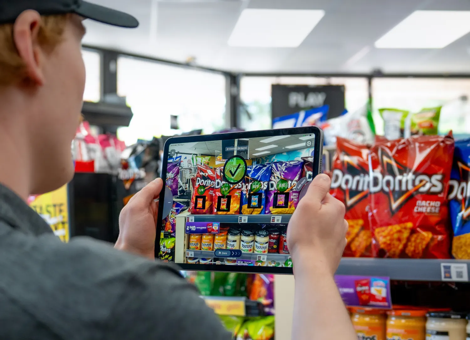 Man scanning a shelf of chips with NomadGo open on a tablet.